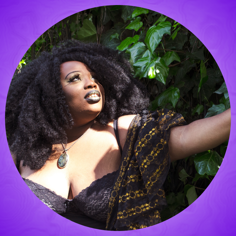 Portrait of Rawiyah, a Black, fat queer non-binary femme from the chest up.Their eyes are open and they are facing the sun. Their face is framed by a cloud of black magnificently kinky hair.